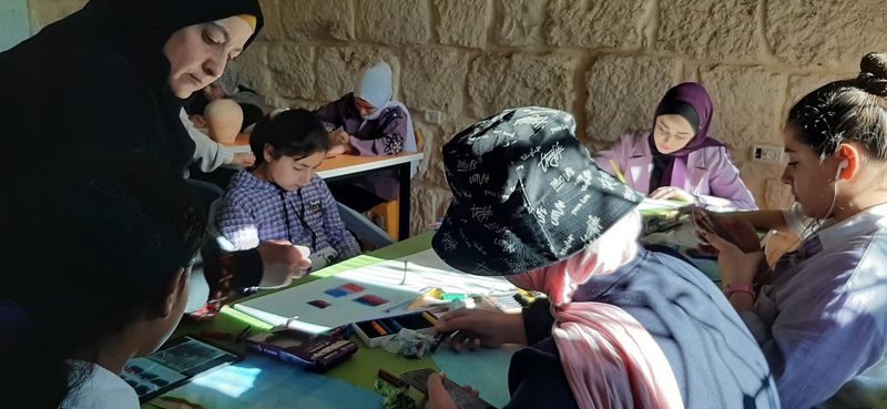 ورشة فنية حول طاولة مشتركة، في غرفة المركز الحجرية.